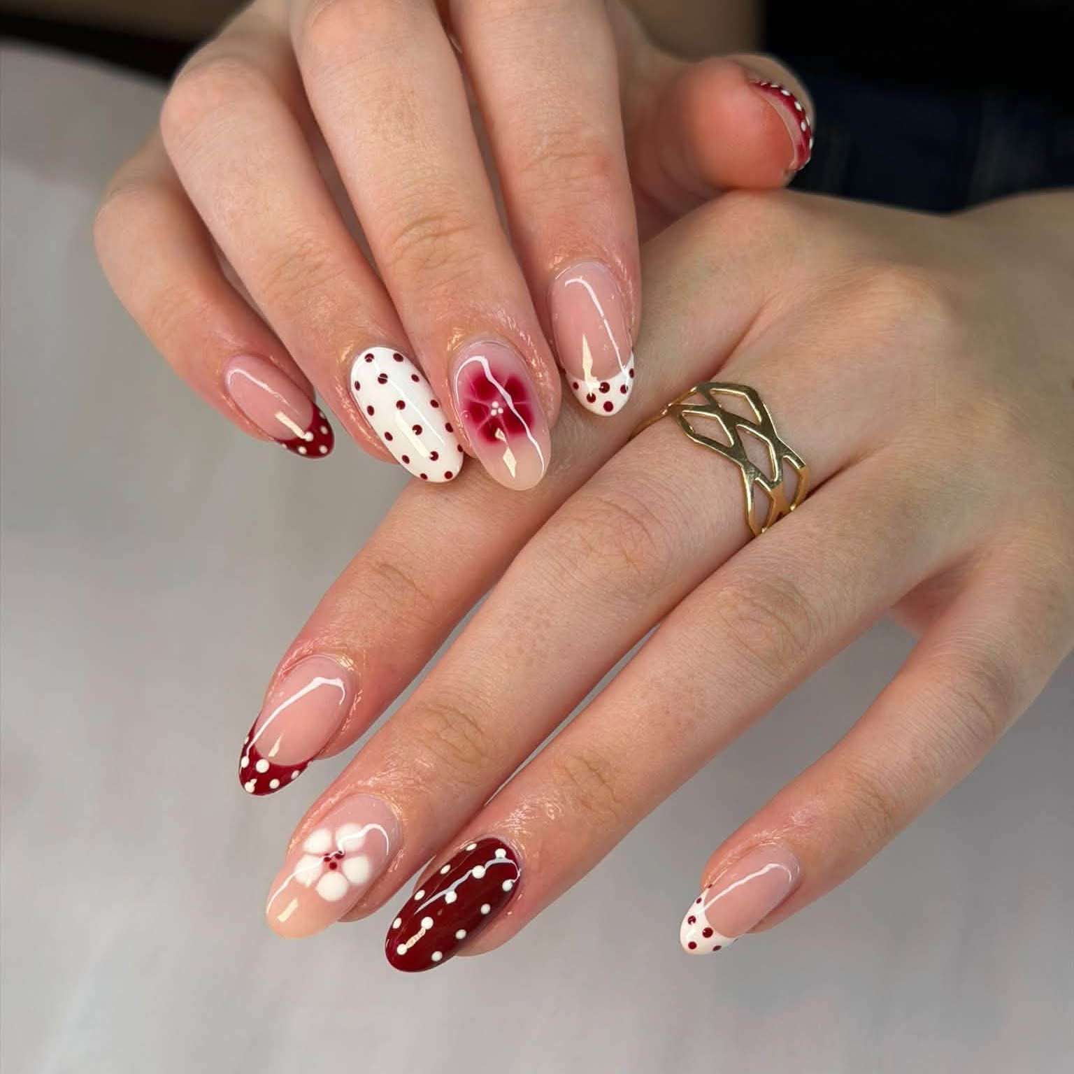 Burgundy and white polka dot nails with a red flower